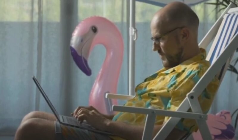 Man working on a laptop in a patio chair, enjoying a sunny day