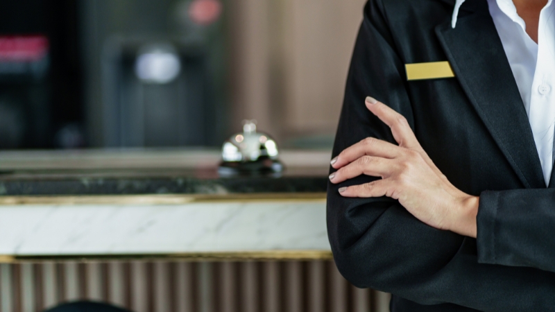 Hotel staff at a reception desk with a service bell, symbolizing accommodations and hospitality